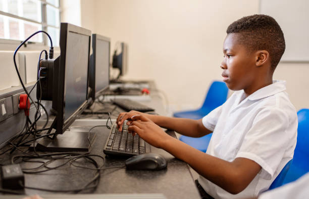 side view of a schoolboy learning computer in class at primary school